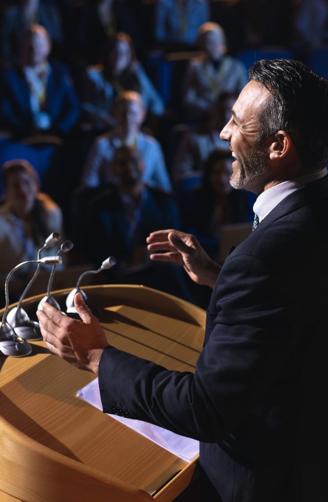 side-view-of-caucasian-businessman-standing-and-giving-presentation-in-the-auditorium.jpg